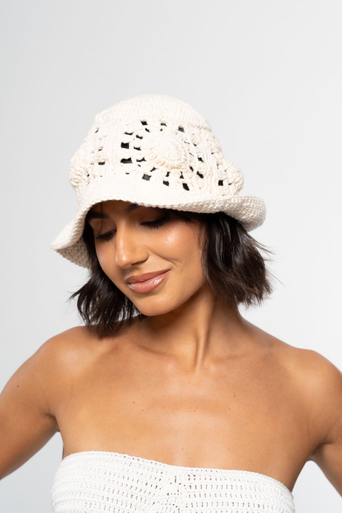 Bucket Puglia de crochê off white, visto de frente com a cabeça inclinada