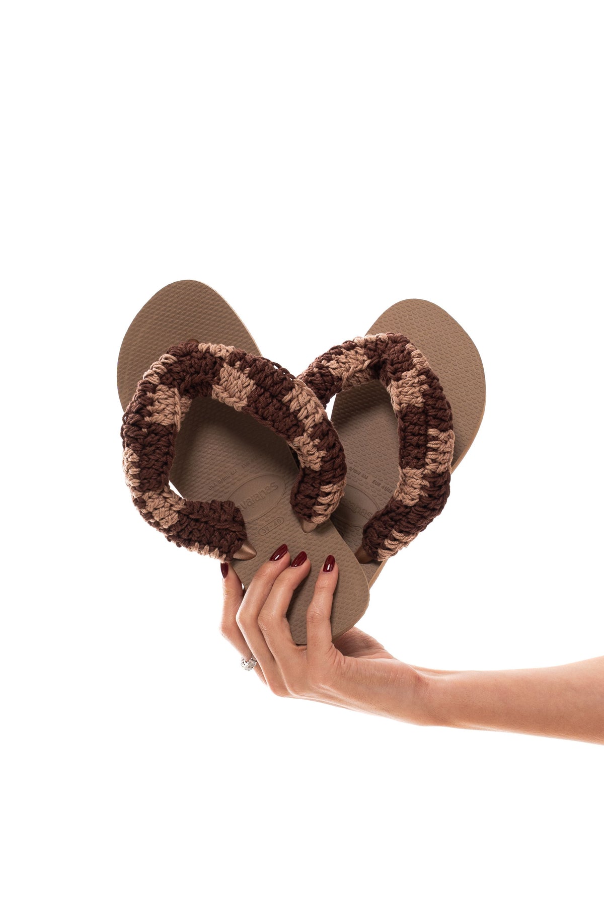 Havaianas Colombina marrom com tiras de crochê marrom e bege, segurada na mão