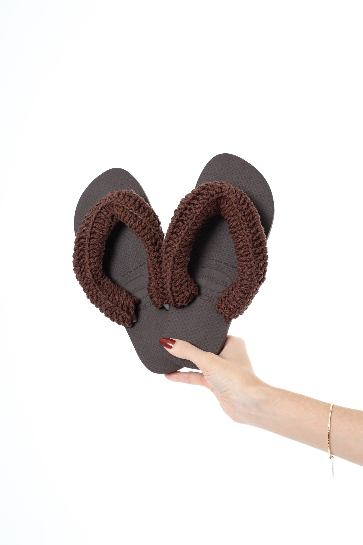 Havaianas marrom com tiras de crochê marrom feito à mão, segurada na mão