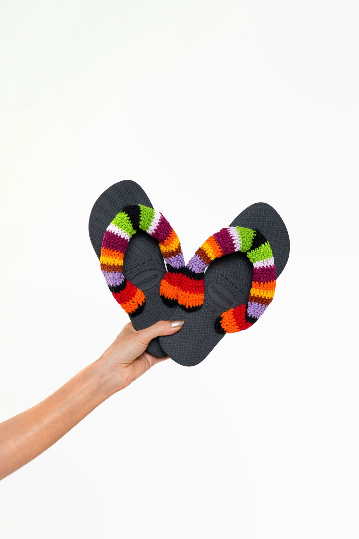Havaianas Portofino preta com tiras de crochê listrado colorido, segurada na mão