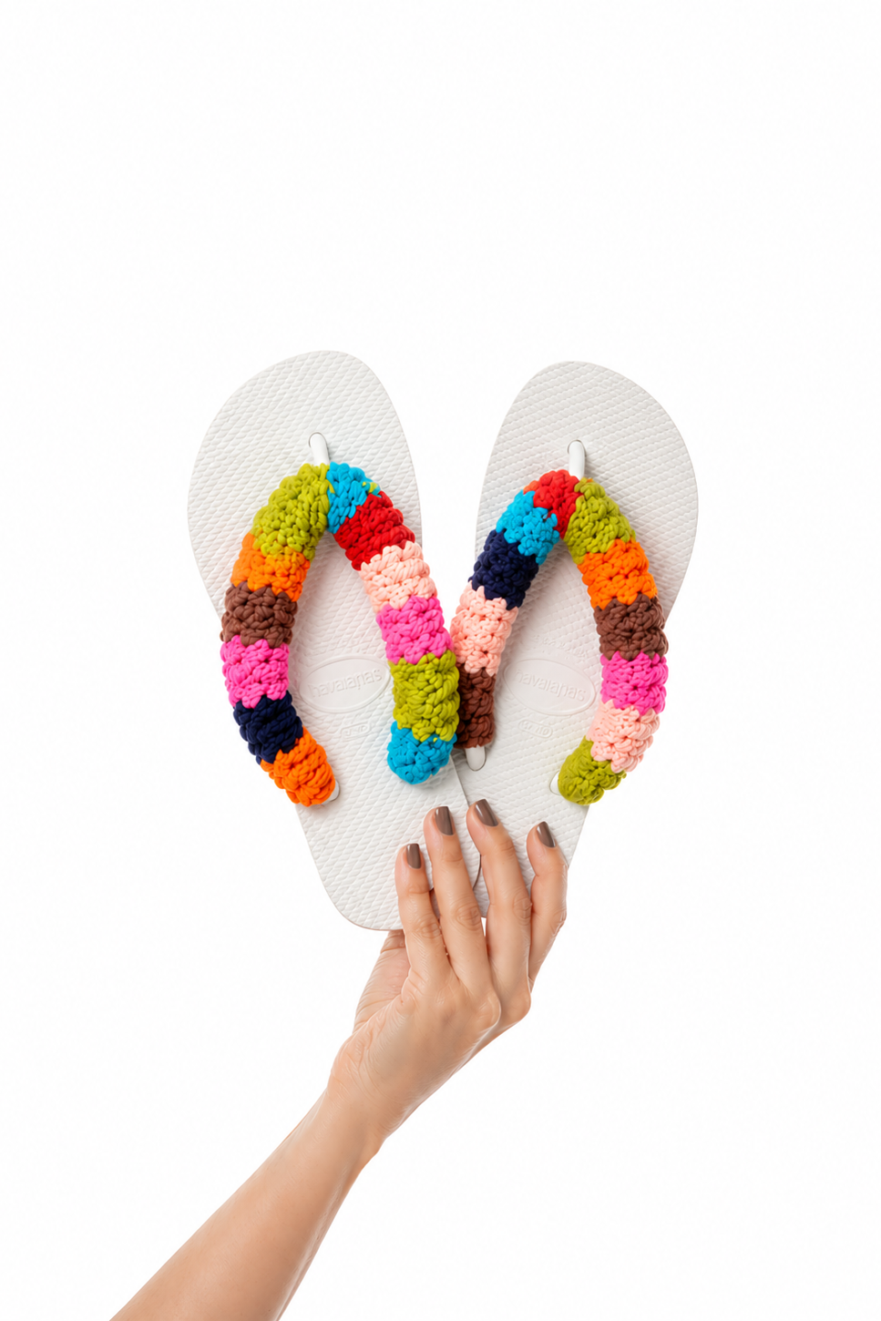 Havaianas Tiê branca com tiras de crochê colorido feito à mão, segurada na mão